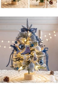Close-up of mini flocked Christmas tree with blue ornaments and warm string lights