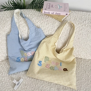 Detail of colorful embroidered letters and bear patch on plaid canvas shoulder bags