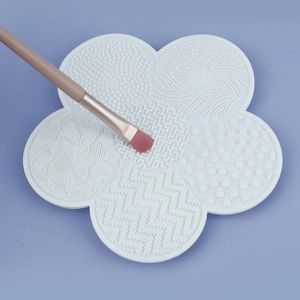 Detail of white flower-shaped silicone makeup brush cleaner mat with various textures