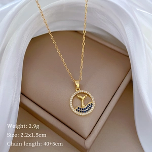 Detailed view of whale tail pendant with blue and white stones on golden titanium necklace