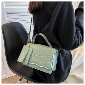 Detail of mint green crocodile pattern handbag with wavy flap and matching mini pouch