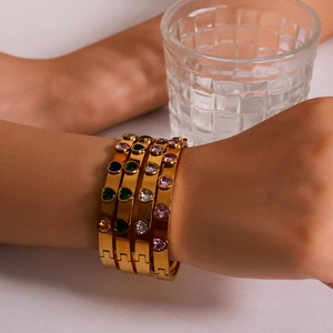 Golden heart-shaped gemstone bracelet set with four colors shown on a model's wrist
