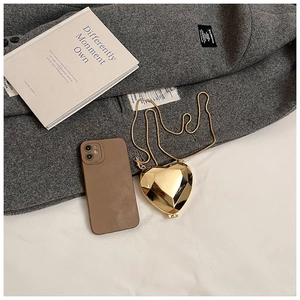 Detailed view of a gold heart-shaped geometric clutch bag styled on a grey wool coat