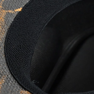 Dettaglio macro del cappello intrecciato maculato con fascia antisudore in maglia nera