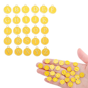 Macro shot of yellow enamel A-Z initial charms with gold alloy frames for DIY jewelry
