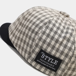Detailed view of vintage plaid newsboy cap featuring black and white checkered fabric pattern