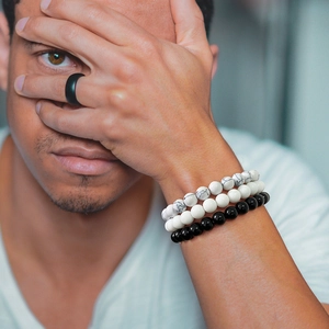 Detail of amethyst layered bead bracelets and black minimalist ring set worn by model