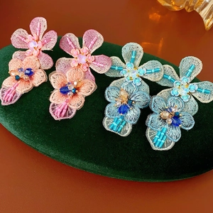 Close-up of handmade floral embroidery charms with pink and blue sequins and beads