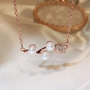 Macro shot of rose gold rose pendant with white pearls and sparkling leaf details