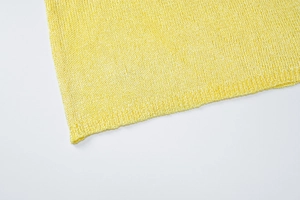 Macro view of bright yellow fine knit fabric showing smooth curled hem craftsmanship