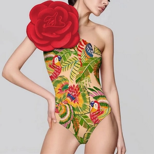 Detail of one-shoulder swimsuit with 3D red rose and vibrant parrot tropical print