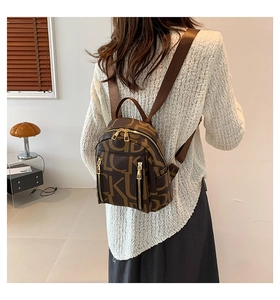 Detailed view of brown letter-patterned backpack with multiple zipper pockets