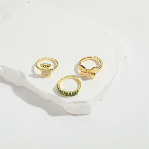 Three gold adjustable rings with bear and butterfly designs on a white stone background