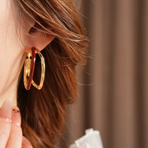 Close-up of retro double-layer hoop earrings in gold and tortoise brown on model's ear