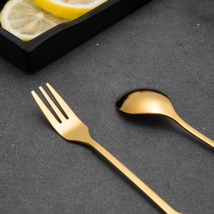 Golden leaf-shaped dessert spoon and fruit fork set on dark stone background table