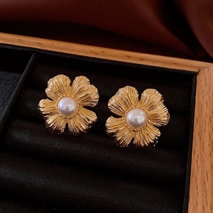 Macro shot of vintage gold flower earrings with pearls on black velvet display