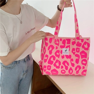 Detail view of pink leopard print canvas tote bag featuring a white woven label on the front