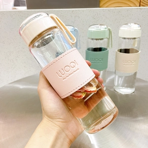 Portable minimalist glass water bottle with pink insulated sleeve and metal tea infuser