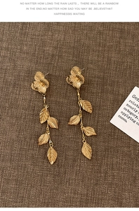 Vue détaillée des boucles d'oreilles fleurs et feuilles dorées au fini martelé