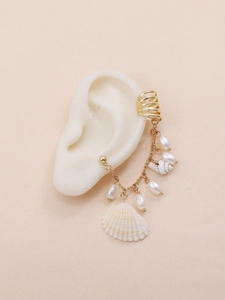 Detailed close-up of shell and pearl tassel earring worn on a silicone ear model