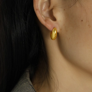 Polished 18K gold plated teardrop bean studs earrings for women on a model's ear