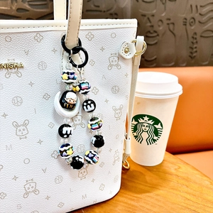 Colorful handmade beaded keychain charm with moon figure hanging on a white tote bag