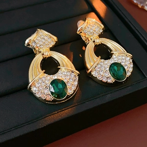 Detail of vintage golden earrings with green gemstones and white rhinestone accents