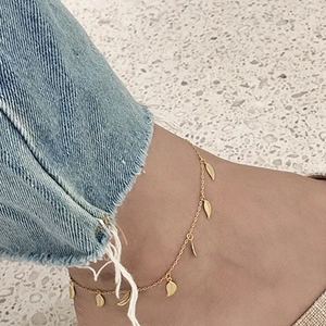Detail shot of the golden leaf charm anklet in 925 sterling silver worn on ankle