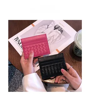 Detail shot of pink and black woven leather card holders in a lifestyle setting