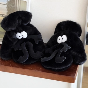 Close-up of black soot sprite plush slippers with large eyes on wooden steps