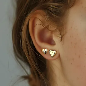 Close-up of asymmetric gold-plated S925 silver heart studs with sparkling zircon stones