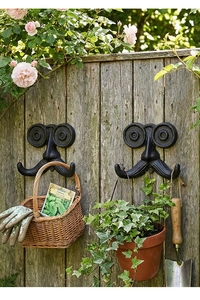 Detalle de ganchos de pared vintage de hierro fundido con forma de bigote en madera