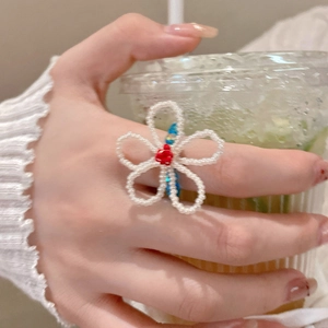 Gros plan d'une bague fleur en perles de cristal faite main portée à la main