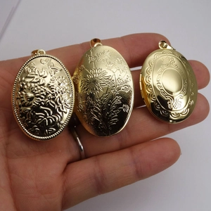 Tres relicarios ovalados dorados con grabados florales vintage mostrados en la mano