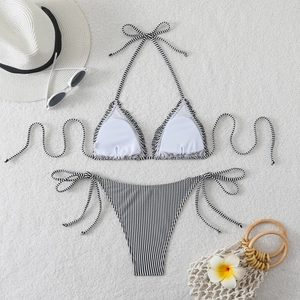 Flat lay of black and white striped bikini set with summer hat and beach accessories