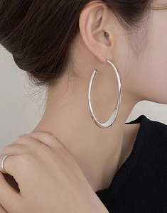 Close-up of polished silver oval hoop earring worn by a model for a minimalist look