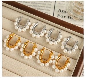 Detailed close-up of U-shaped gold and silver earrings with elegant white pearls