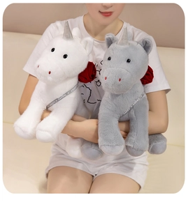 Detail of plush unicorn toy with red rose and Happy Lucky ribbon in model's arms