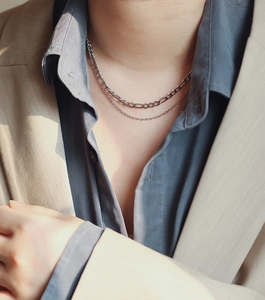 Close-up of double layer silver Figaro and cable chain necklace on a model