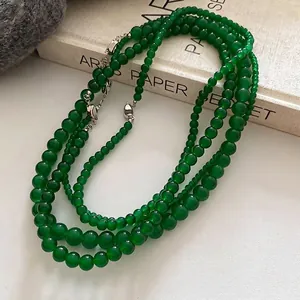 Collier multi-rangs en perles vertes avec fermoir argenté sur fond de livre vintage