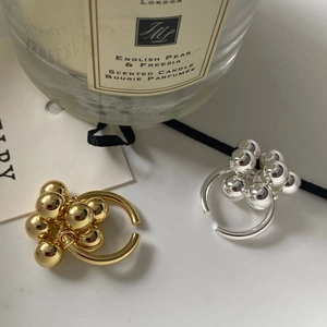 Anillo abierto de racimo en latón dorado y plateado sobre fondo blanco elegante y refinado