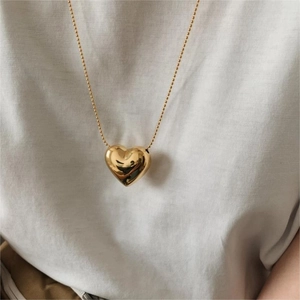 Detailed view of a 3D puffed heart pendant on a delicate gold ball chain necklace