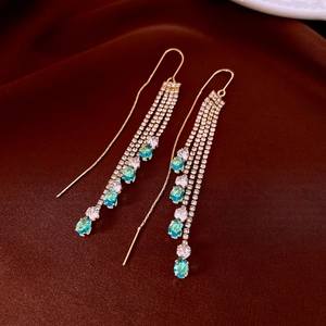 Detail of gold tassel earrings with lake blue and white drop-shaped zircon crystals