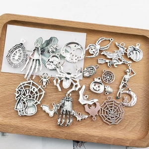 Detailed flat lay of assorted vintage silver Halloween charms in a wooden tray for DIY