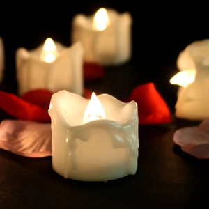 Close-up of LED tea light candles with warm yellow glow and scattered rose petals