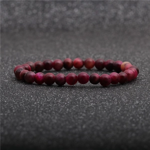 Detail of rose red tiger eye stone bracelet with smooth polished beads on dark background