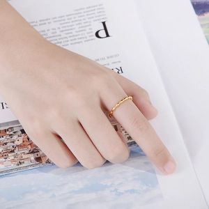 Minimalist gold beaded stainless steel ring shown on finger over a lifestyle magazine