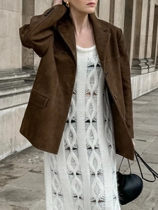 Detail of dark brown faux suede blazer paired with a white crochet knit midi dress