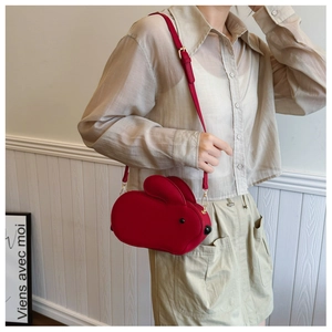 Détail du sac bandoulière lapin rouge avec ferrures dorées porté en scène de vie