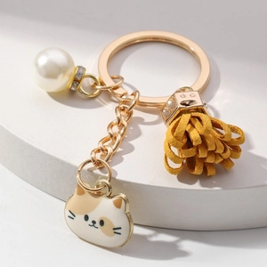 Cute kitten keychain with golden chain, faux pearl, and yellow suede tassel on white base